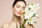 Woman Beauty Face Portrait with Lily Flower. Model Girl with Smooth Skin Make up. Spa Care and Relaxing Cosmetology Concept. Beige