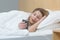 Woman in bed under the blanket shocked, reading good news from the phone smiling