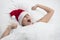 Woman in bed yawning with Santa hat