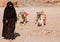 Woman Bedouin in black clothes against the background of lying camels.