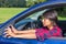 Woman behind steering wheel adjusting car mirror