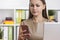 Woman in beige looking at phone screen, closeup