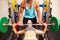 Woman bench pressing weights with assistance of trainer, front view