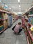 A woman bent down while shopping for goods in a supermarket.