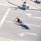 Woman on a bicycle, between left and right arrow signs - view from above with long shadows