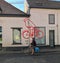 Woman bicycles past bicycle logo painted on De Koninck building