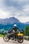 Woman biker with adventure touring motorcycle in full equipment on dirt road,