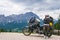 Woman biker with adventure touring motorcycle in full equipment on dirt road,