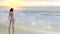 Woman in bikini on beach watching sunset