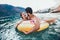 Woman in bikini floating on inflatable ring and her boyfriend in sea