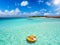 A woman in bikini and with hat relaxes on a round float over the turquoise sea of the Maldives