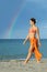 Woman in bikini and pareo walking on beach