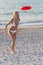 Woman In Bikini Playing Frisbee At A Beach