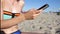 Woman in bikini sms texting using app on smart phone at the beach. Closeup of hands using smartphone outdoors. Mobile