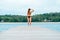 Woman in bikini walking down a tropical jetty