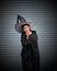 Woman with black cape and witch hat use her hands to strangle her neck on stripe metal background