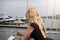 Woman in a black cocktail dress is standing on the open balcony in the yacht club with a glass of white wine