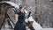 Woman in black dress in fairy tale image stands in snow in winter forest