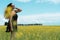 Woman on black dress posing in profile on yellow field full of wild flowers on a farmland