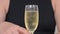 Woman in black dress takes glass of champagne close view