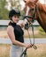 Woman with a black helmet stroking a chestnut horse head, close up shot