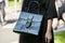 Woman with black leather bag with French motto before Giorgio Armani fashion show, Milan Fashion Week street