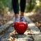 Woman in black leggings with red apple on footpath in autumn forest. Healthy lifestyle concept