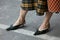 Woman with black low heel pointed shoes and black and yellow checkered shirt before Giorgio Armani fashion show,