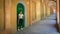 Woman in black pants holding thermos and standing in front of green door in portico