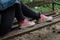 Woman in black ripped jeans and pink canvas sneakers sitting alone on  bench