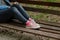 Woman in black ripped jeans and pink canvas sneakers sitting alone on  bench