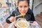 A woman in black sweater is eating Udon from chopsticks