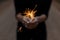 Woman in a black T-shirt celebrates the holiday with amazing sparklers. Female hands with sparkler close-up. Focus on bright fire.