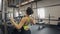 Woman in black training suit pumps iron in Fitness-station in gym.