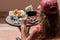 Woman blogger taking a picture on mobile phone  plate with lamb potato and salad on the table outside on the balcony. Top view.