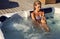 woman with blond hair in bikini relaxing in outdoor whirlpool