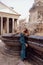 woman with blond hair in luxurious black evening dress and accessories posing near famous monument Pantheon n in Rome