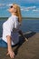 Woman with blond hair, on the pier, against the blue lake and sky,sunbathing, close-up