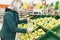 Woman blonde in a medical mask chooses fruit in a supermarket. Quarantine during the coronavirus pandemic