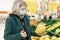 Woman blonde in a medical mask chooses fruit in a supermarket. Quarantine during the coronavirus pandemic