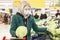 Woman blonde in a medical mask chooses vegetables in a supermarket. Self-isolation in a pandemic