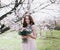 Woman in blooming trees. Woman with wedding bouquet in hands.