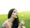 Woman blowing dandelion on the meadow