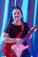 Woman with blue afro hairstyle musician guitarist playing electric guitar at a concert.