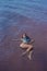 A woman in a blue bikini swims on her back in a salt lake. Miracle of nature pink lake. Deposit and extraction of salt