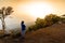 Woman in blue coat looking sunset at cliff in winter