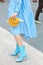 Woman with blue dress, high heel leather boots and yellow reptile leather bag before Sportmax