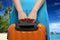 Woman in blue dress holds orange suitcase in hands