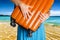 Woman in blue dress holds orange suitcase in hands