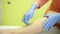 Woman in blue gloves performs a shugaring procedure